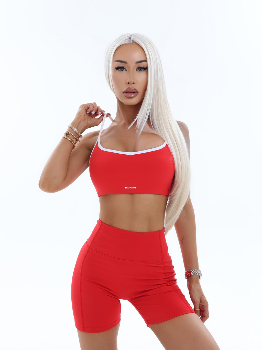 Woman wearing a red activewear bra and shorts set on a white background