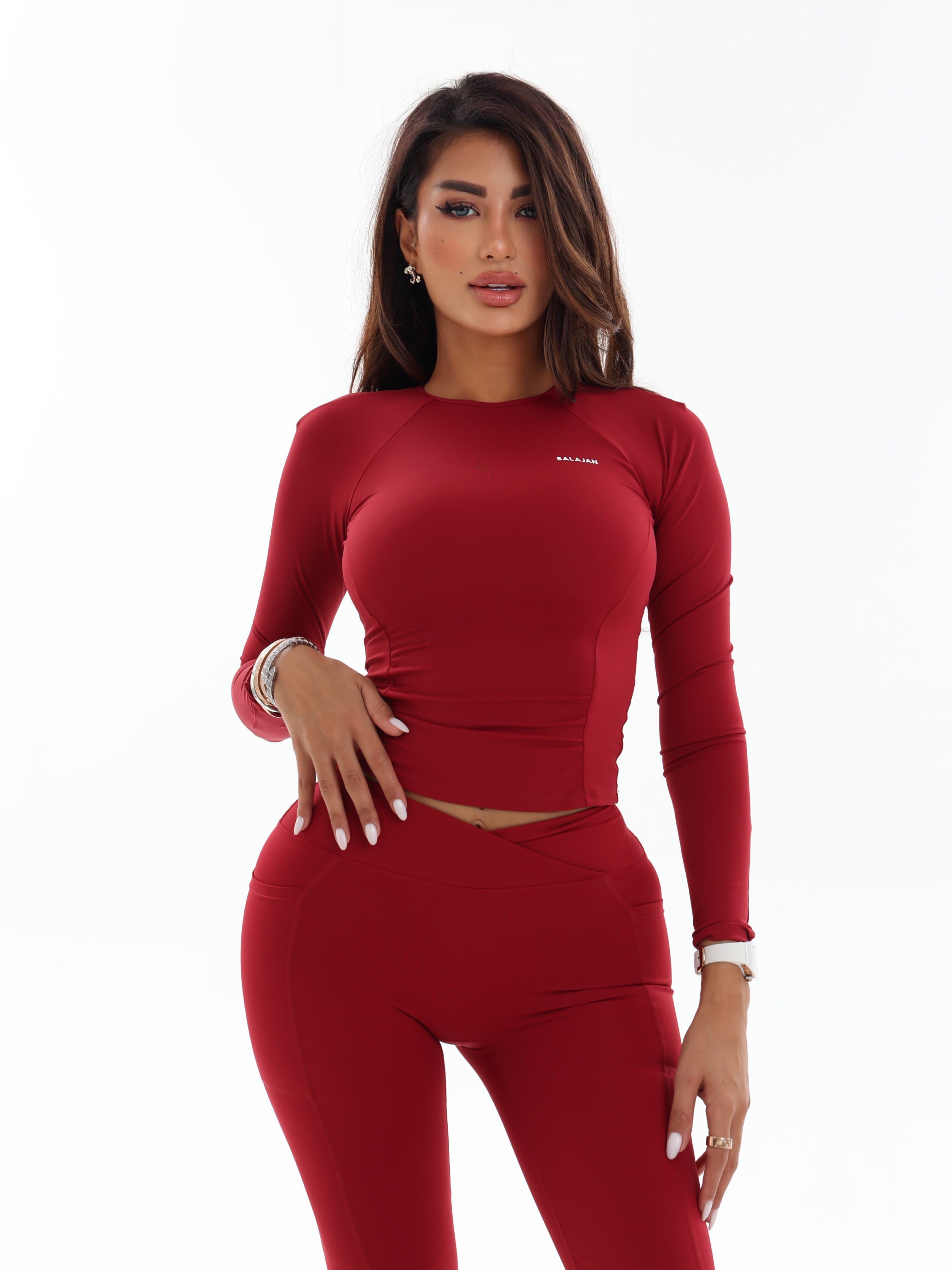 Woman wearing a red athletic Long Sleeve Top on a white background