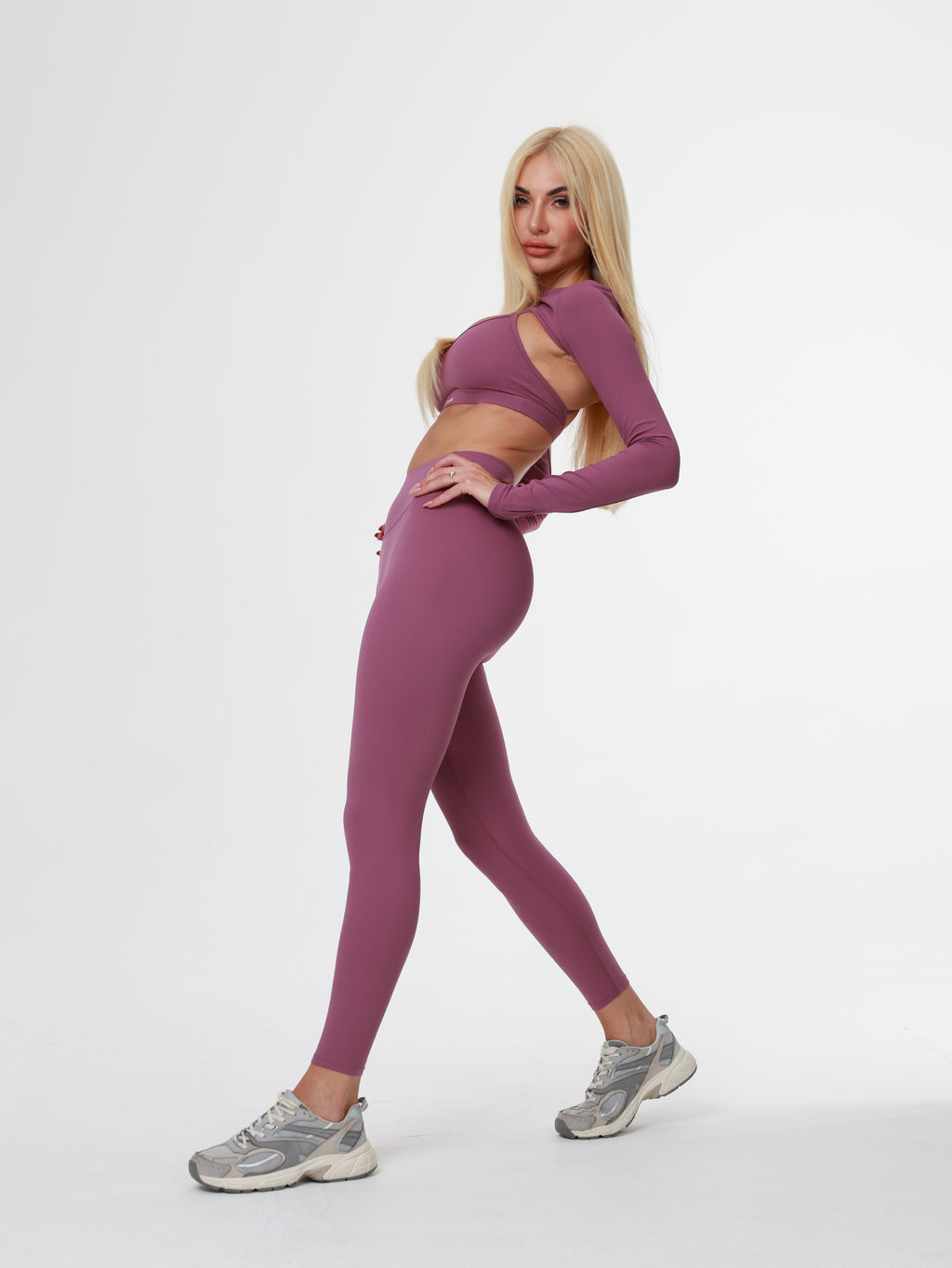 Person in purple Amethyst Leggings , bra and long sleeve top wear posing on a white background