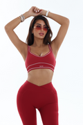 Woman wearing a red activewear sports bra and leggings set on a white background