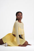 Woman wearing a yellow activewear Lumia skirts sitting on a white background