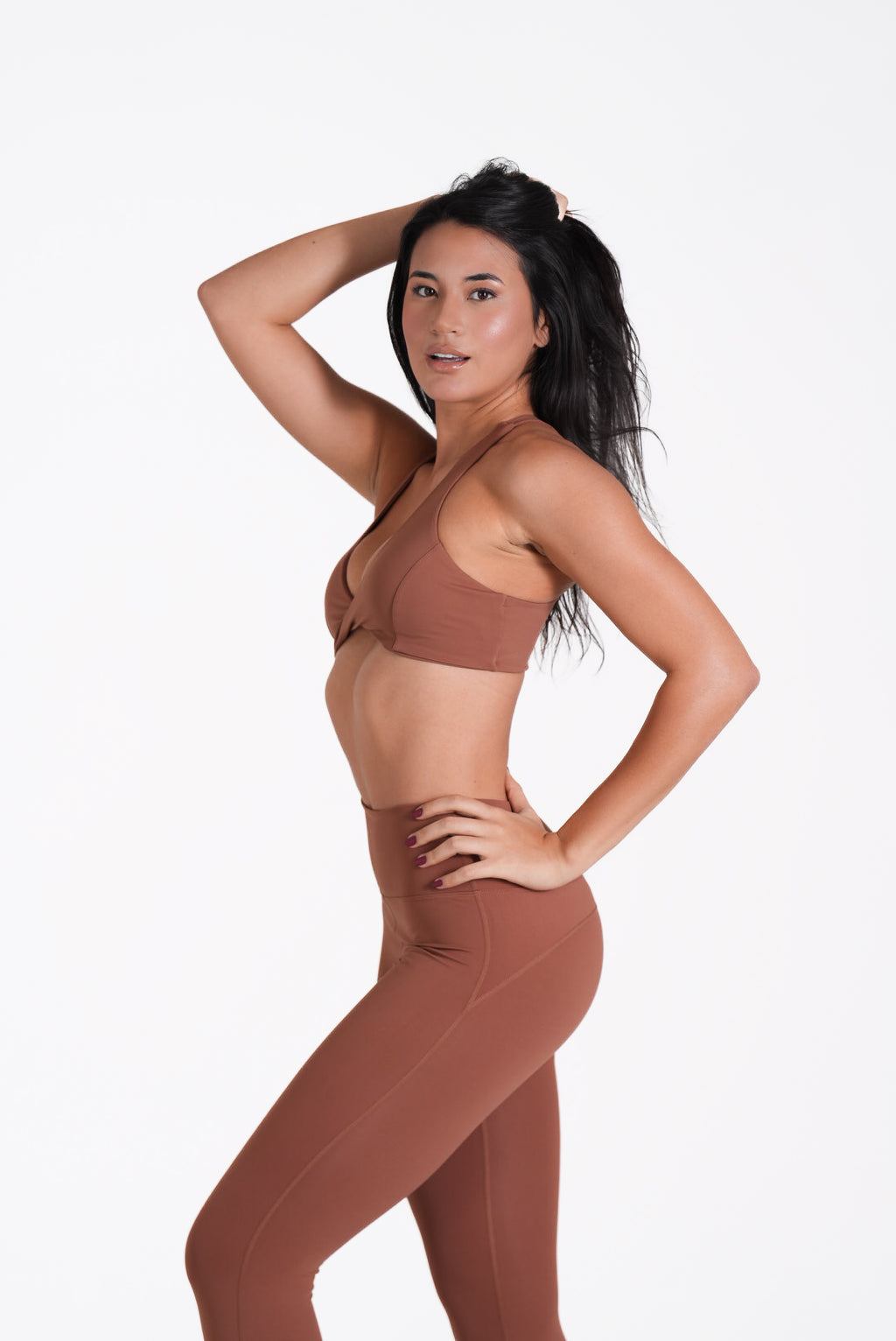 Woman wearing a brown sports bra and Eterna Wave Leggings' set on a white background