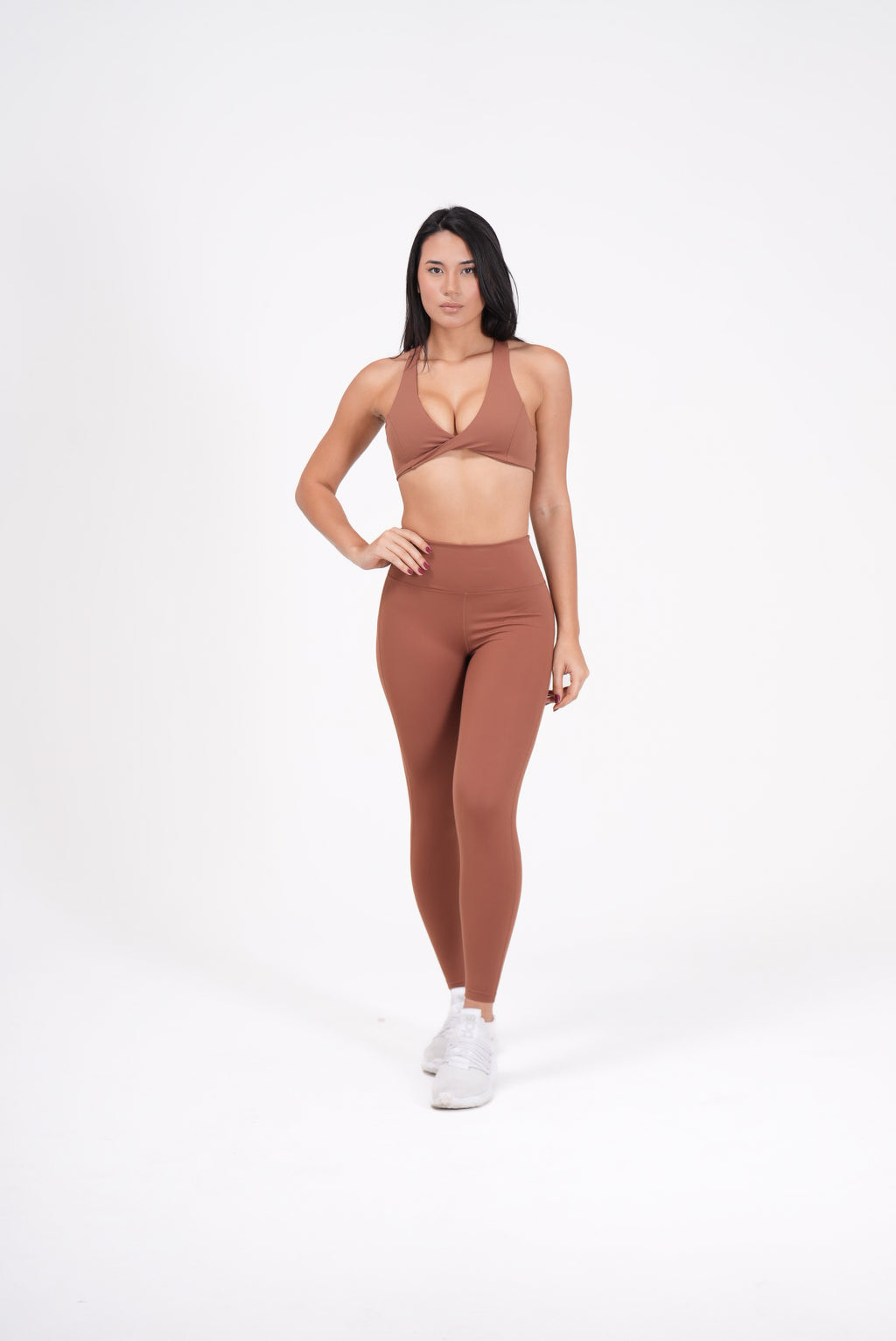 Woman wearing a brown sports bra and Eterna Wave Leggings' set on a white background