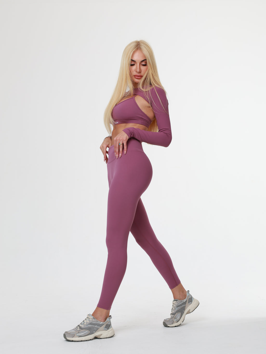 Person in purple Amethyst Leggings , bra and long sleeve top posing on a white background
