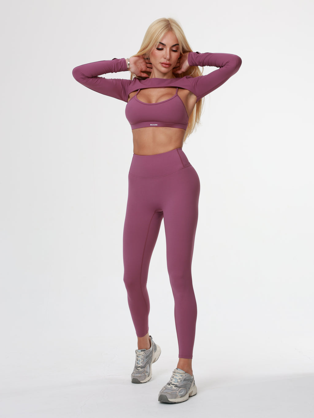Person wearing a purple athletic Amethyst Leggings , bra and long sleeve top on a white background