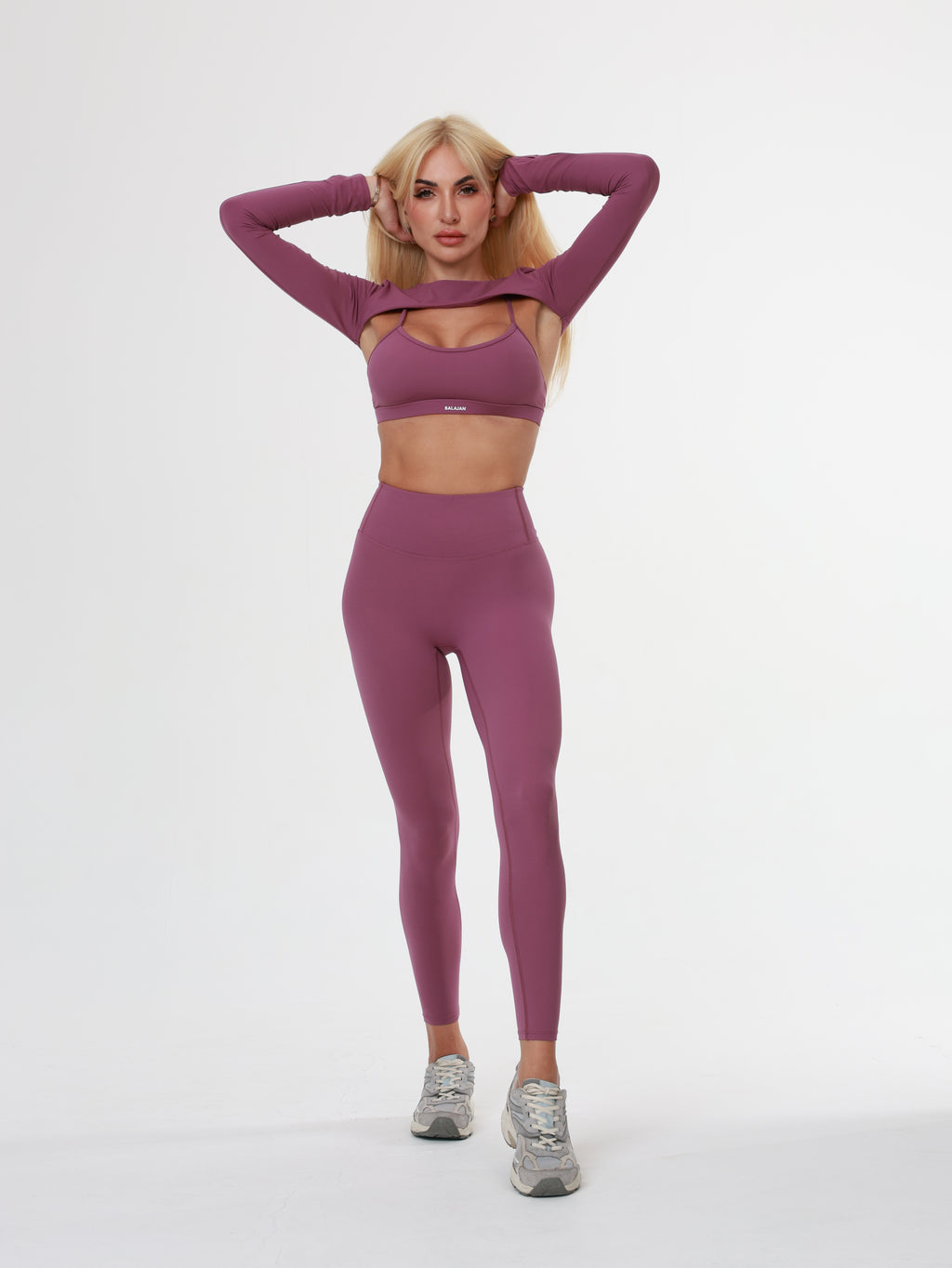 Person wearing a purple athletic Amethyst Leggings , bra and long sleeve top on a white background