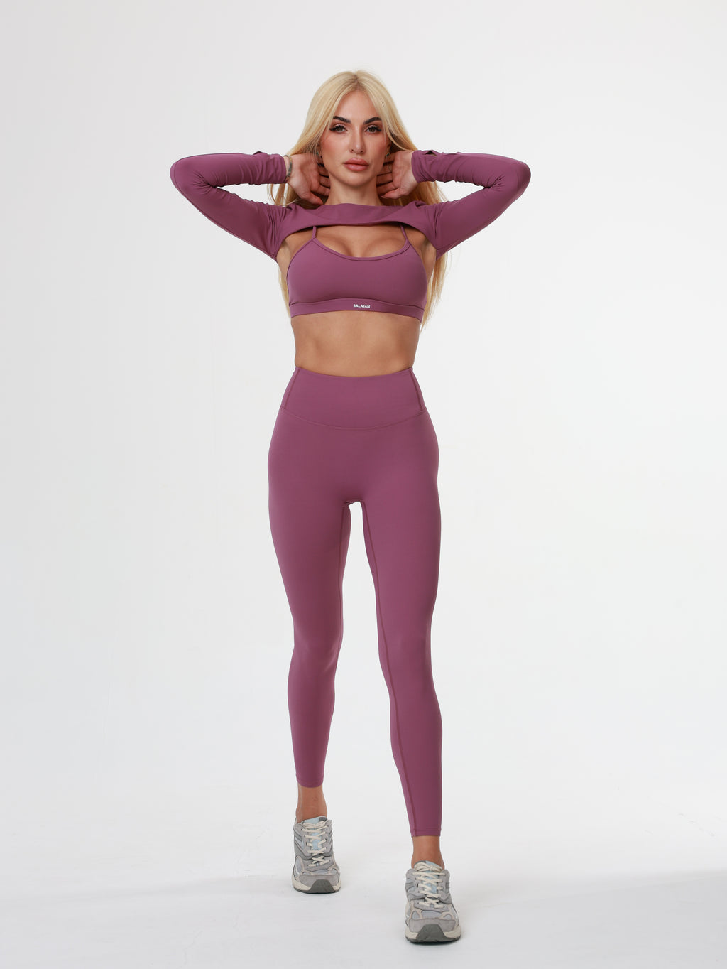 Person wearing a purple athletic Amethyst Leggings , bra and long sleeve top on a white background