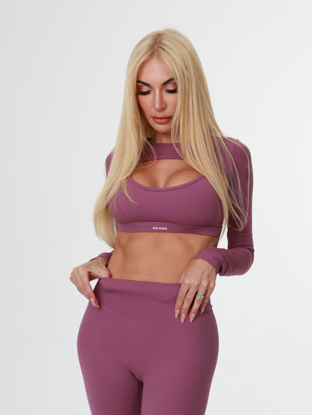 Woman wearing a purple athletic Amethyst Sculpt Bra with leggings on a white background