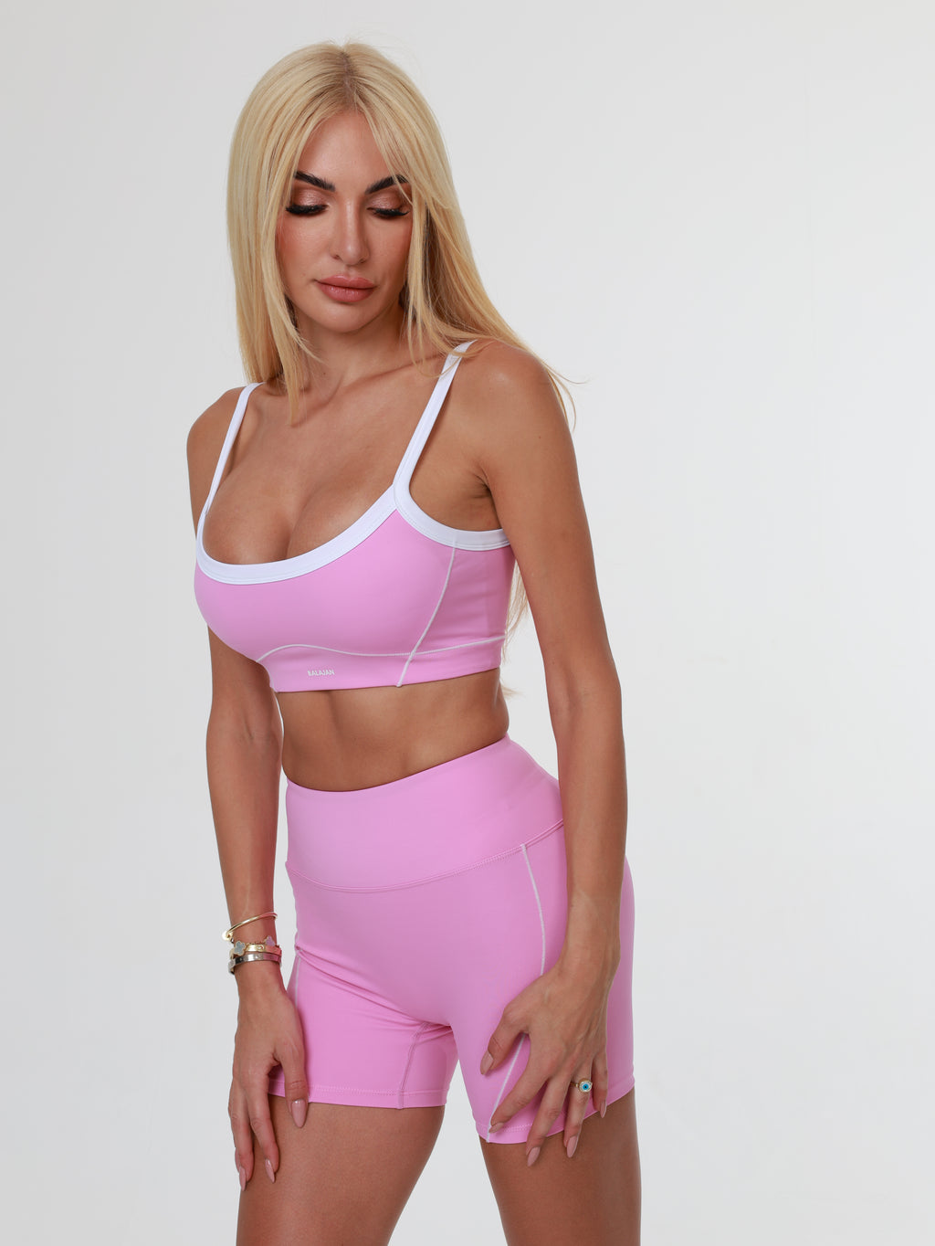 Woman wearing a pink athletic Blush Babe Sculpt Shorts and bra on a white background