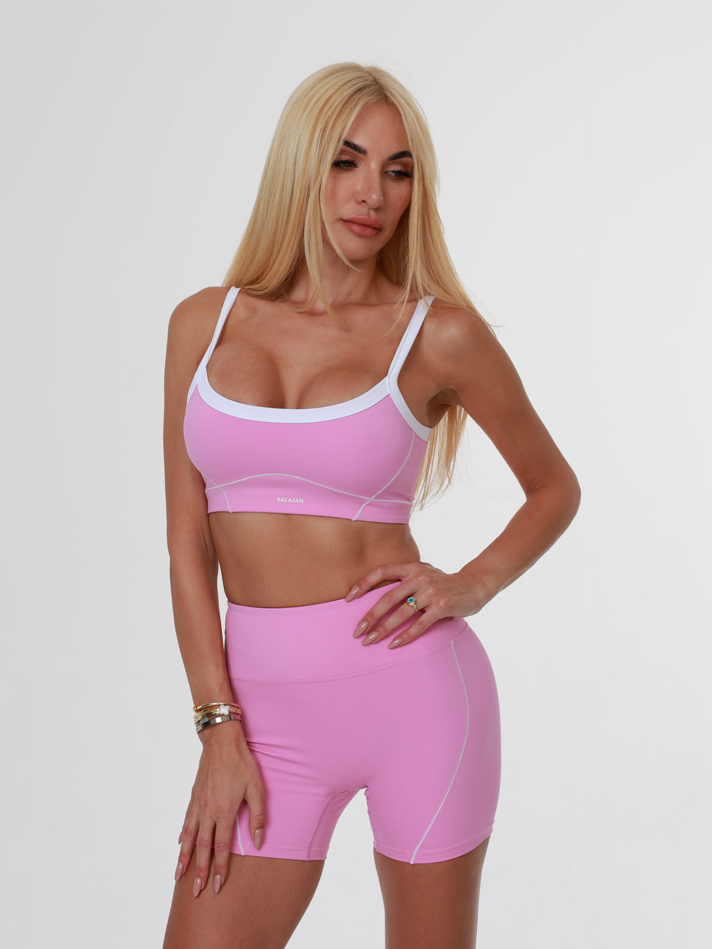 Woman wearing a pink Blush Babe Sculpt sports bra and shorts on a white background