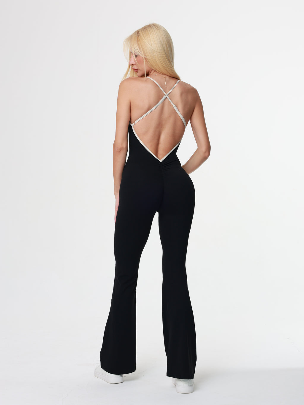 women wearing a black bodysuit and white sneakers on a white background