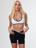 Woman wearing a white sports bra and black Eclipse-Glow Shorts on a light gray background