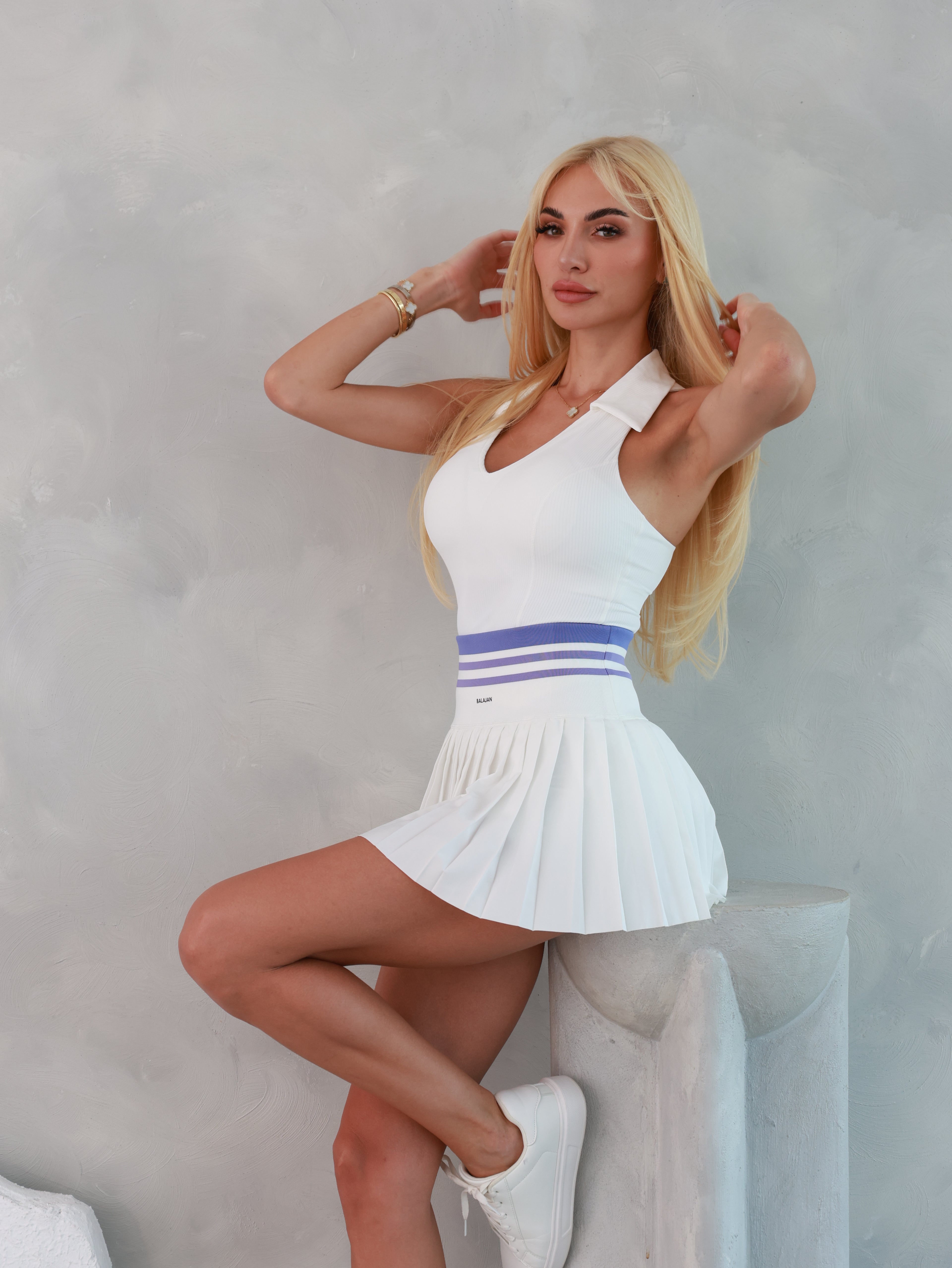Woman in a white Hamptons Skirt with a blue stripe lying on a white surface