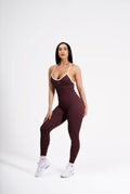 Woman wearing a maroon activewear bodysuit with white accents on a white background