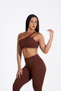 Woman wearing a brown sports bra and leggings set on a white background