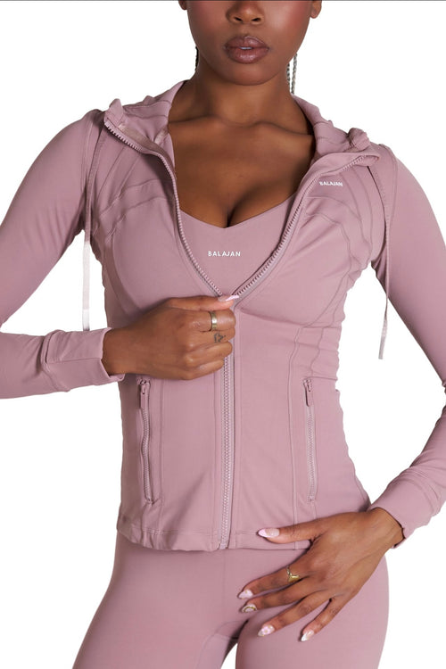 Person wearing a pink athletic Core Sol Jacket' with a hood on a white background