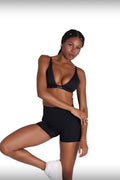 Woman wearing a black sports bra and Sculpt Shorts on a white background