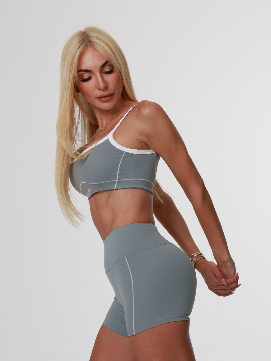 Woman in gray athletic Storm Motion Short wear posing on a white background