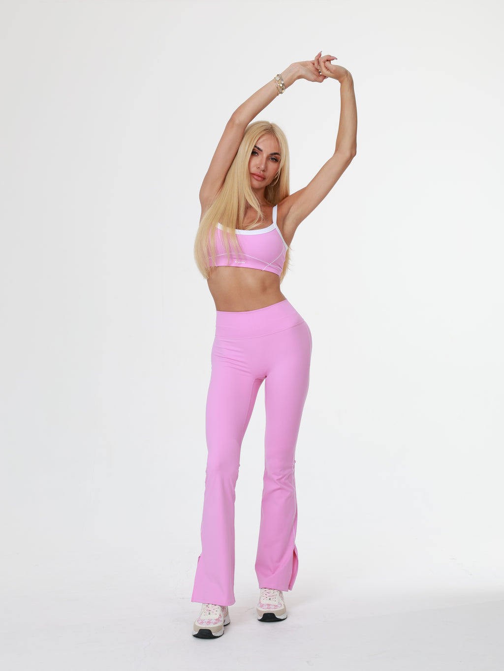 Woman in pink flare leggings lying on a white background