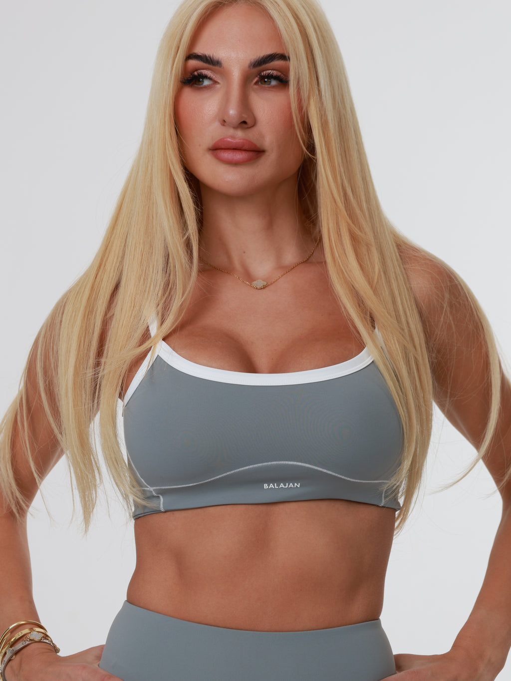 Woman wearing a gray sports bra and leggings on a white background
