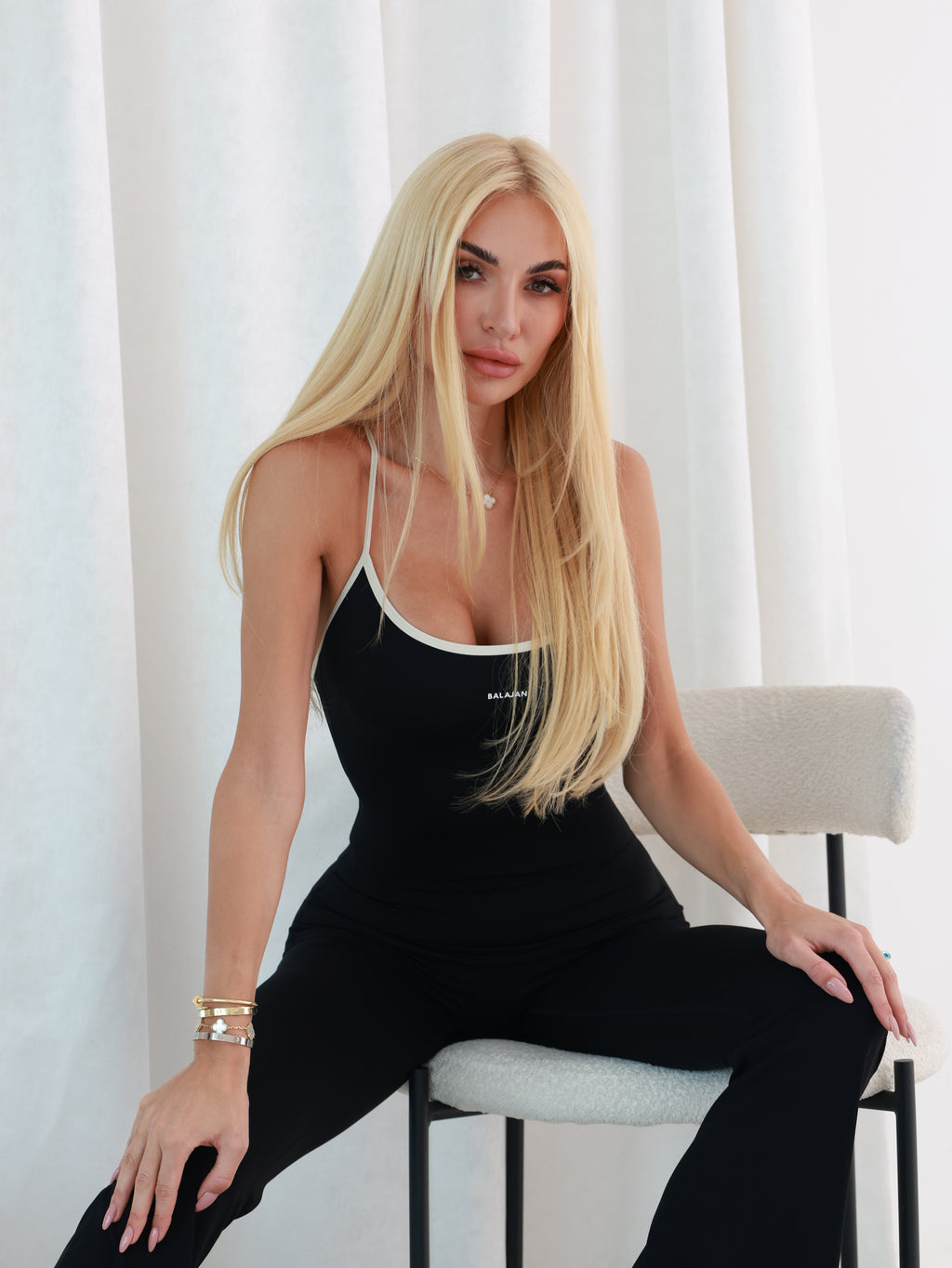 Woman in a black activewear bodysuit posing in a minimalistic room.